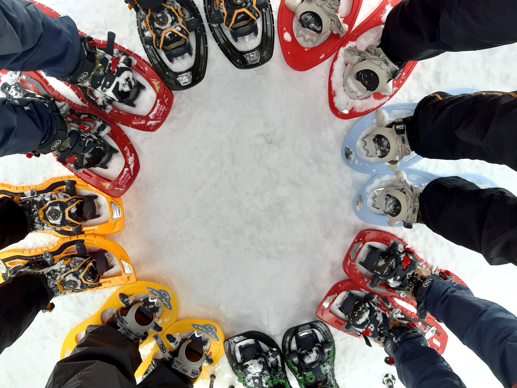 Vue sur des pieds chaussés de raquettes en cercle dans la neige