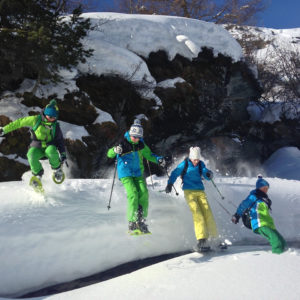 Quatre enfants sautant en raquette dans la neige